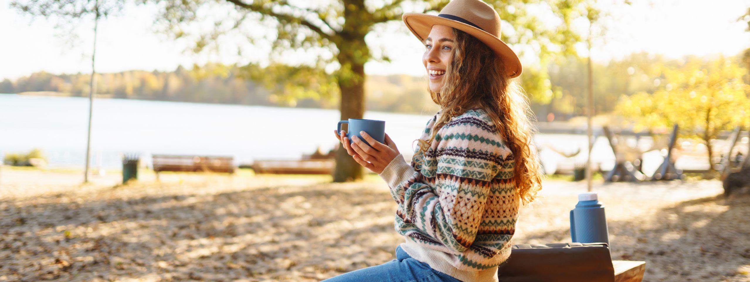 A lady taking time to enjoy a hot drink outside in Autumn