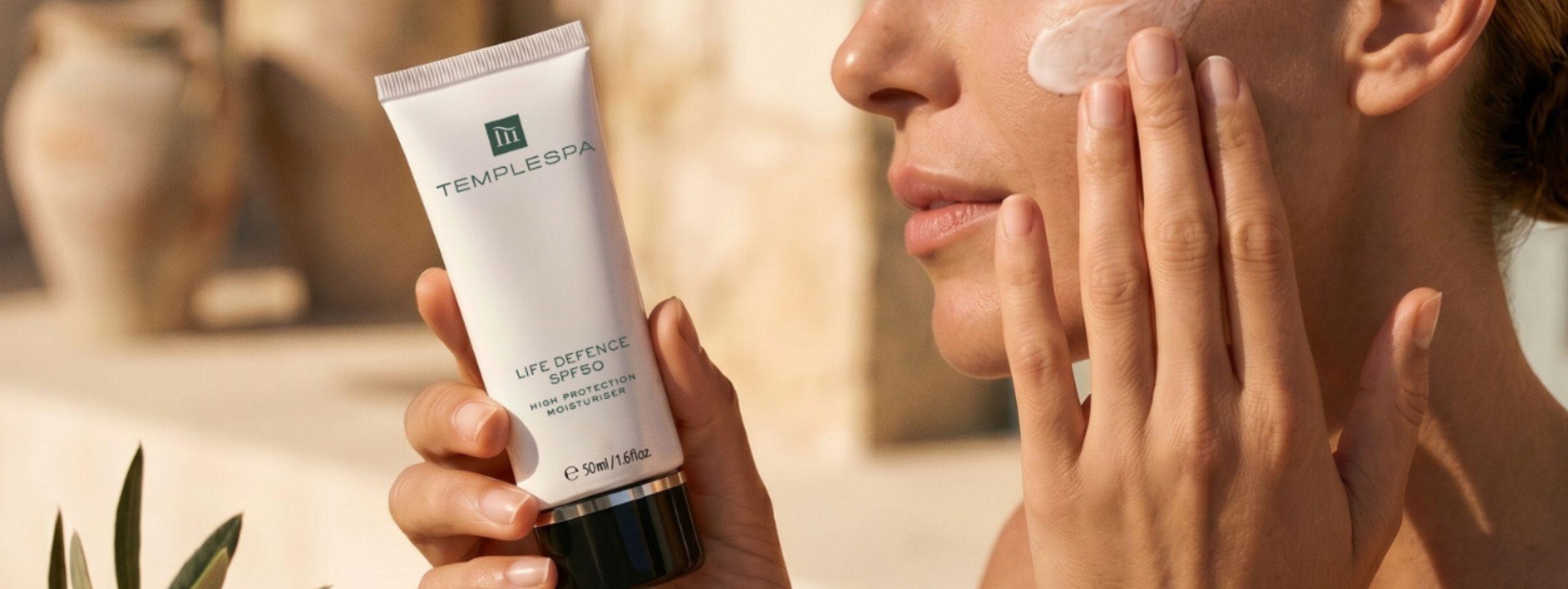 LIFE DEFENCE sunscreen moisturiser is being applied to a woman's face in readiness for enjoying the sunshine. 