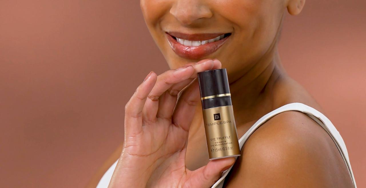 Eye truffle eye cream being held by a model and she is smiling