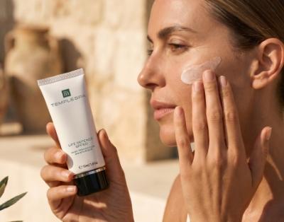 LIFE DEFENCE sunscreen moisturiser is being applied to a woman's face in readiness for enjoying the sunshine. 